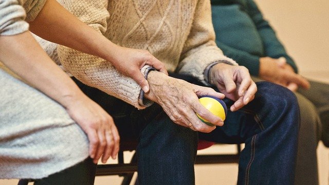 Younger Lady Holding the Arm of an Elderly Man Sitting Down Offering Companionship Services in Tampa, Florida