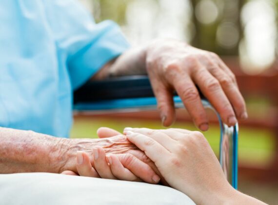 hands touching with a lady on a wheelchair receiving Senior Care in Largo, FL, Pasco County, Pinellas County, Tampa, Clearwater, Hillsborough County and Surrounding Areas