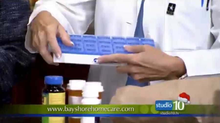 A home health aide holds a pill organizer with bottles of pills on a table in Holiday, FL